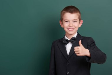 okul çocuk göstermek en iyi jest, portre yeşil boş kara tahta arka plan, yakınındaki giyinmiş klasik siyah takım elbise, bir öğrenci, eğitim kavramı