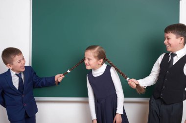 Çocuk oyun ve eğlenmek, çocuklar kız örgüler, boş okul kara tahta arka plan, giyinmiş klasik siyah takım elbise, grup öğrenci, eğitim kavramı yakınındaki çekin.