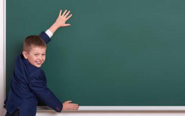 İlköğretim Okulu çocuk kara tahta arka plan üzerinde el koymak ve boşluk giyinmiş klasik siyah takım elbise, grup öğrenci, eğitim kavramı göstermek