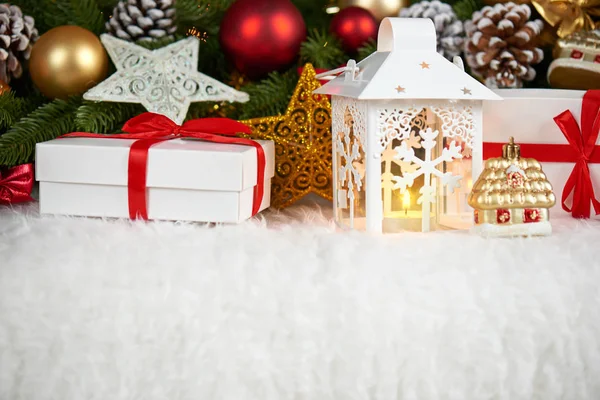 Decoração de natal em pele branca com abeto ramo de árvore closeup, presentes, bola de xmas, cone e outros objetos no fundo escuro com luzes, conceito de férias de inverno — Fotografia de Stock