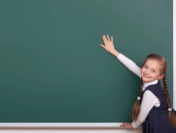 小学女孩把双手放在黑板背景和显示空白，穿着黑色西装，组学生，教育理念 — 图库照片