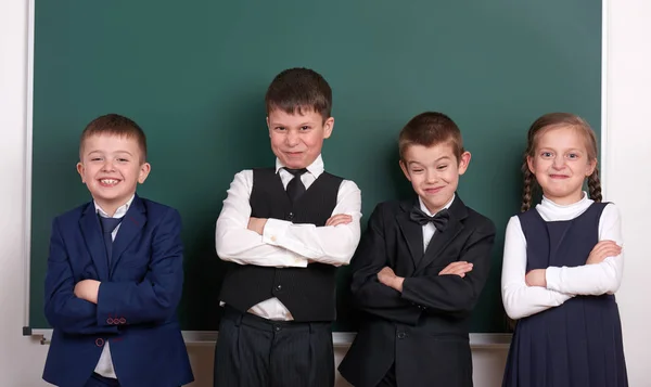 Gruppenschüler als Bande, posierend in der Nähe von leerem Kreidetafelhintergrund, Grimassen und Emotionen, gekleidet in einen klassischen schwarzen Anzug — Stockfoto