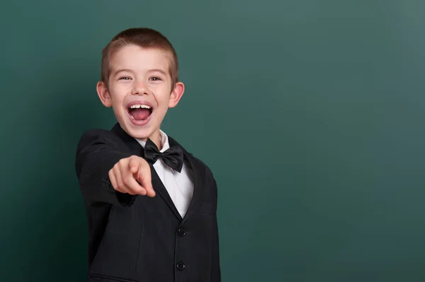 School boy point the finger near blank chalkboard background, dressed in classic black suit, group pupil, education concept — Stock Photo, Image