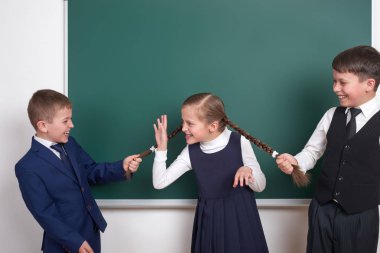 Çocuk oyun ve eğlenmek, çocuklar kız örgüler, boş okul kara tahta arka plan, giyinmiş klasik siyah takım elbise, grup öğrenci, eğitim kavramı yakınındaki çekin.