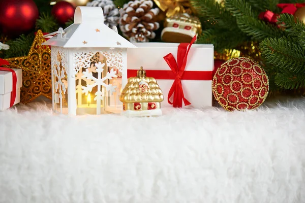 Decoração de natal em pele branca com abeto ramo de árvore closeup, presentes, bola de xmas, cone e outros objetos no fundo escuro com luzes, conceito de férias de inverno — Fotografia de Stock