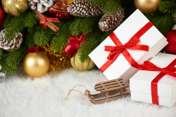 Χριστουγεννιάτικη διακόσμηση closeup υποκατάστημα δέντρο έλατου, ξύλινο έλκηθρο παιχνίδι, δώρα, Χριστούγεννα μπάλα, κώνος και άλλο αντικείμενο στο λευκό κενό διάστημα γούνα, έννοιας διακοπές, τοποθετήστε για κείμενο — Φωτογραφία Αρχείου