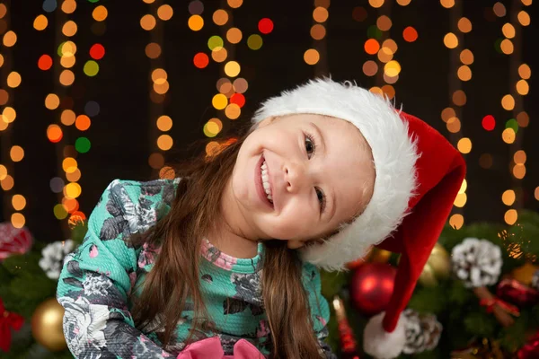 Bambino ragazza ritratto in decorazione di Natale, emozioni felici, concetto di vacanza invernale, sfondo scuro con illuminazione e luci boke — Foto Stock