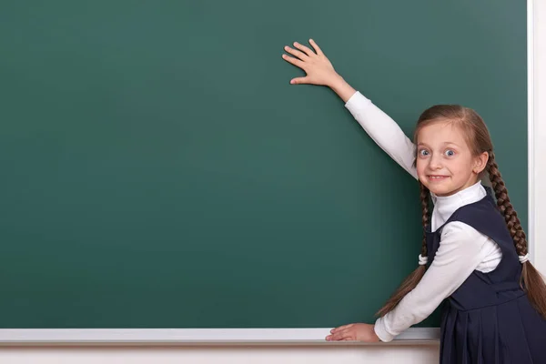 Écolière primaire mettre la main sur le fond de tableau et montrer l'espace vide, habillé en costume noir classique, élève de groupe, concept d'éducation — Photo