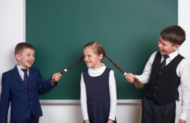 Çocuk oyun ve eğlenmek, çocuklar kız örgüler, boş okul kara tahta arka plan, giyinmiş klasik siyah takım elbise, grup öğrenci, eğitim kavramı yakınındaki çekin.