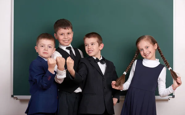 Gruppenschüler als Bande, posierend in der Nähe von leerem Kreidetafelhintergrund, Grimassen und Emotionen, gekleidet in einen klassischen schwarzen Anzug — Stockfoto