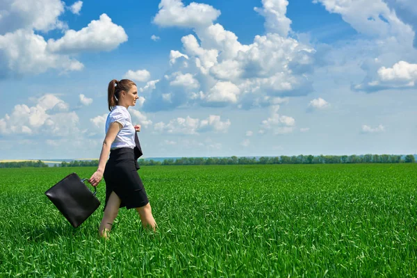 Mujer de negocios caminar en campo de hierba verde al aire libre. Hermosa joven vestida de traje, paisaje de primavera, día soleado brillante — Foto de Stock
