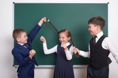Çocuk oyun ve eğlenmek, çocuklar kız örgüler, boş okul kara tahta arka plan, giyinmiş klasik siyah takım elbise, grup öğrenci, eğitim kavramı yakınındaki çekin.