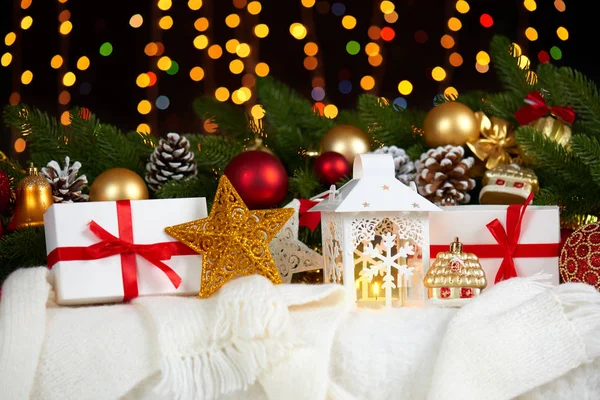 Decoración de Navidad en piel blanca con abeto rama primer plano, regalos, bola de Navidad, cono y otro objeto sobre fondo oscuro con luces, concepto de vacaciones de invierno —  Fotos de Stock