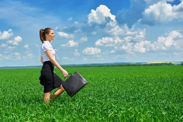 Mujer de negocios caminar en campo de hierba verde al aire libre. Hermosa joven vestida de traje, paisaje de primavera, día soleado brillante — Foto de Stock