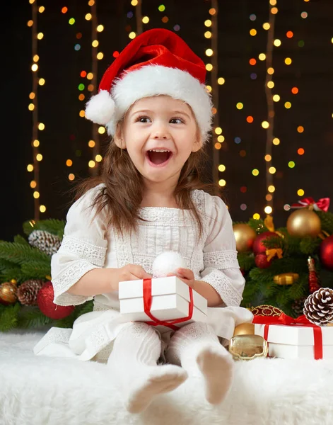 Retrato de niña en la decoración de Navidad, emociones felices, concepto de vacaciones de invierno, fondo oscuro con iluminación y luces de arco — Foto de Stock