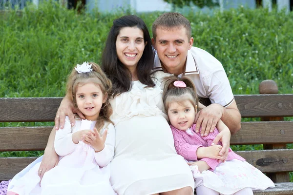 Šťastná rodina v létě městský park venkovní, těhotná žena, rodiče a děti, jasný slunečný den a zelené trávy, krásné lidi, portrét — Stock fotografie
