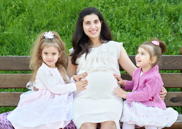 Mulher grávida e crianças no parque da cidade de verão ao ar livre, família feliz, dia ensolarado brilhante e grama verde, retrato de pessoas bonitas — Fotografia de Stock