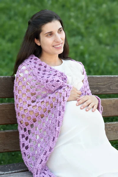 Těhotná žena portrét, sedět na lavici v létě městský park, jasný slunečný den a zelené trávy, krásní lidé portrét — Stock fotografie