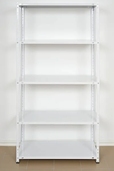 Rack de metal branco perto da parede, prateleiras vazias — Fotografia de Stock