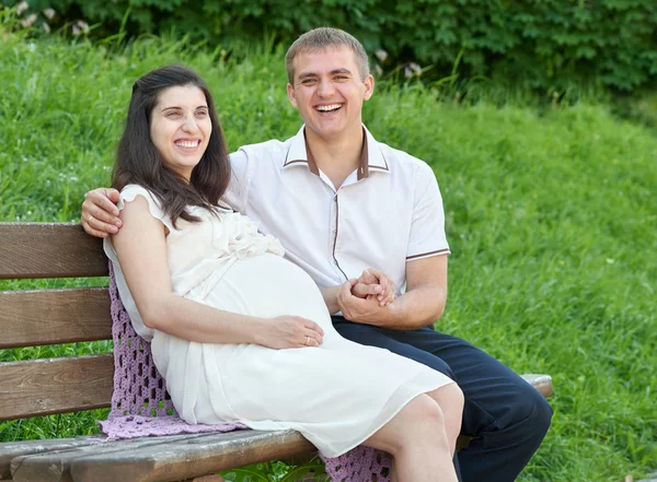 Casal feliz no parque da cidade de verão ao ar livre, mulher grávida, dia ensolarado brilhante e grama verde, retrato de pessoas bonitas — Fotografia de Stock