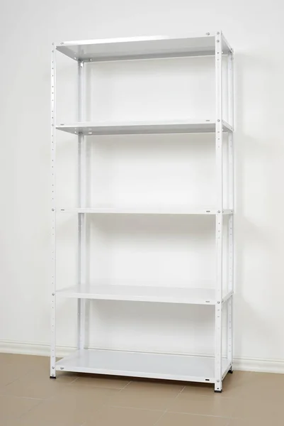Estante de metal blanco cerca de la pared, estantes vacíos —  Fotos de Stock