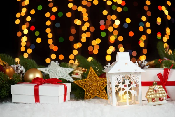 Juldekoration på vit päls med fir tree gren närbild, gåvor, xmas ball, kon och andra objekt på mörk bakgrund med ljus, vinter semester koncept — Stockfoto