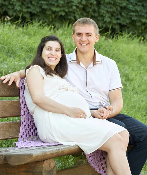 Couple heureux dans le parc de la ville d'été en plein air, femme enceinte, belle journée ensoleillée et herbe verte, beau portrait de personnes, ton jaune — Photo