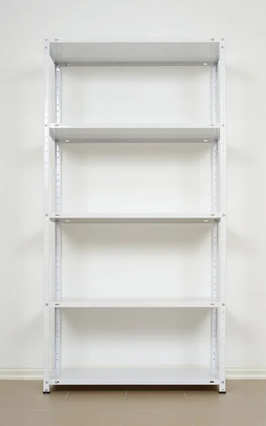 Rack de metal branco perto da parede, prateleiras vazias — Fotografia de Stock