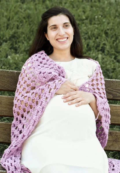 Pregnant woman portrait, sit on bench in summer city park, bright sunny day and green grass, beautiful people portrait, yellow toned — Stock Photo, Image