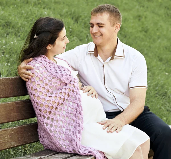 Счастливая пара в летнем городском парке на открытом воздухе, беременная женщина, яркий солнечный день и зеленая трава, красивые люди портрет, желтый тонированный — стоковое фото