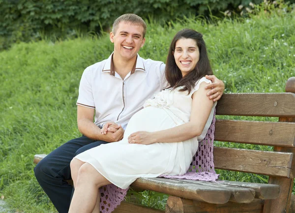Šťastný pár v létě city parku venkovní, těhotná žena, jasný slunečný den a zelené trávy, krásní lidé portrét, žluté laděných — Stock fotografie