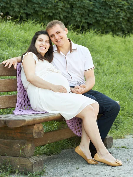 Casal feliz no parque da cidade de verão ao ar livre, mulher grávida, dia ensolarado brilhante e grama verde, retrato de pessoas bonitas, amarelo tonificado — Fotografia de Stock