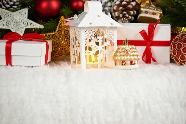 Χριστουγεννιάτικη διακόσμηση σε άσπρο fur με closeup υποκατάστημα δέντρο έλατου, δώρα, Χριστούγεννα μπάλα, κώνος και άλλο αντικείμενο σε σκούρο φόντο με φώτα, χειμερινές διακοπές έννοια — Φωτογραφία Αρχείου
