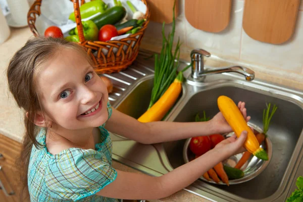 child girl washing vegetables and fresh fruits in kitchen interior, healthy food concept