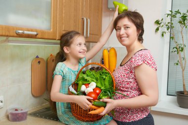 Anne ve kızı mutfak iç sebze ve taze meyve sepeti ile eğleniyor. Üst ve alt. Sağlıklı gıda kavramı