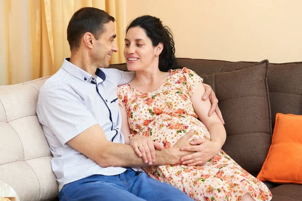 Těhotná žena a muž fotografování portrétů, šťastní lidé sedí na pohovce — Stock fotografie