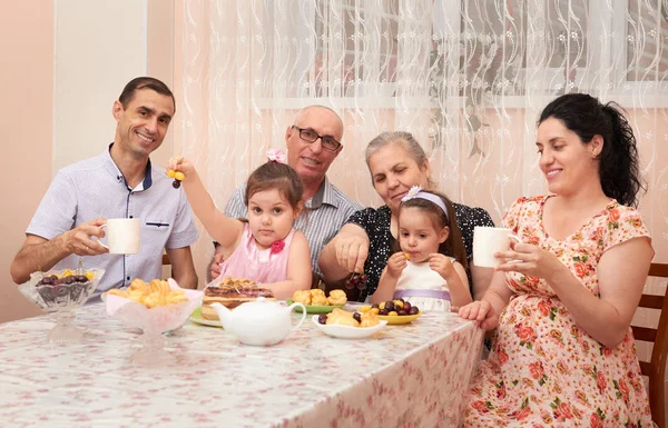 big family drinking tea in dining room, pregnant woman