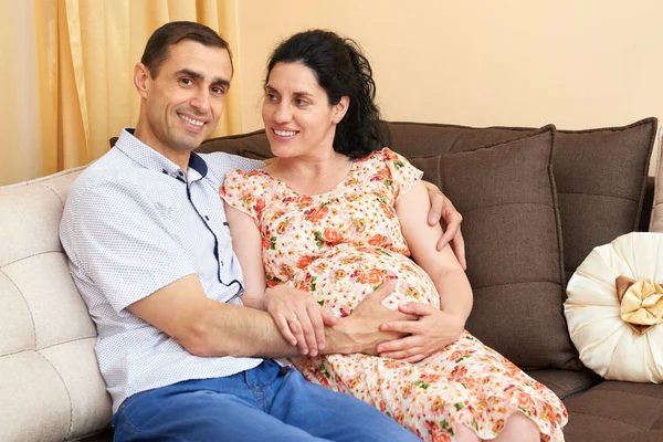 Těhotná žena a muž fotografování portrétů, šťastní lidé sedí na pohovce — Stock fotografie