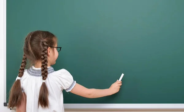 Schoolgirl writing chalk on a blackboard, empty space, education concept — Stock Photo, Image