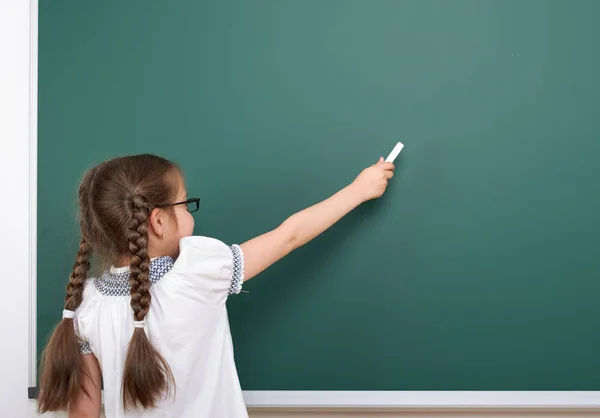 Schoolgirl writing chalk on a blackboard, empty space, education concept — Stock Photo, Image