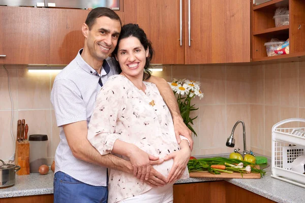 Casal no interior da cozinha com frutas e legumes frescos, conceito de comida saudável, mulher grávida e homem — Fotografia de Stock