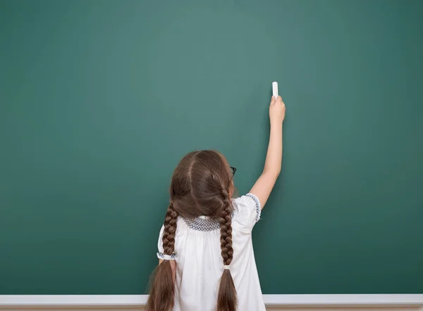 Colegiala escribiendo tiza en una pizarra, espacio vacío, concepto de educación — Foto de Stock