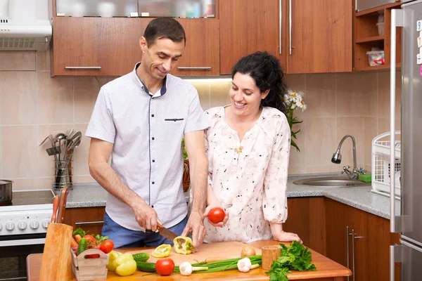 用新鲜的水果和蔬菜，健康食品的概念，怀孕的女人和男人在厨房室内烹饪的夫妇 — 图库照片