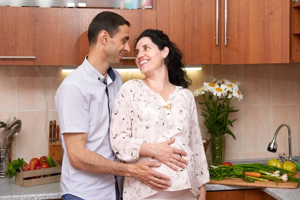 Paar in keuken interieur met verse groenten en fruit, gezonde voeding concept, zwangere vrouw en man — Stockfoto