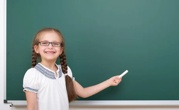 Colegiala escribiendo tiza en una pizarra, espacio vacío, concepto de educación — Foto de Stock