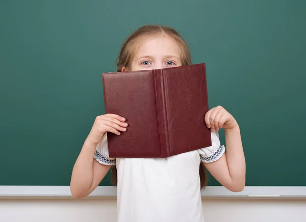 School girl read book, posing at school board, empty space, education concept — Stock Photo, Image