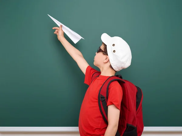 Studente con aereo di carta giocare vicino a una lavagna, spazio vuoto, concetto di istruzione — Foto Stock