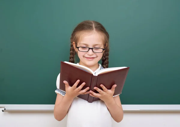 School girl read book, posing at school board, empty space, education concept — Stock Photo, Image