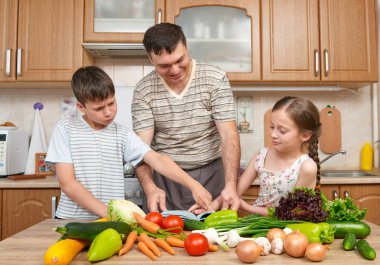 Baba ve iki çocuk yemek kitabı ve seçim yemekleri okuma. Mutlu aile, kız ve erkek ev mutfak iç meyve ve sebze ile eğleniyor. Sağlıklı gıda kavramı.