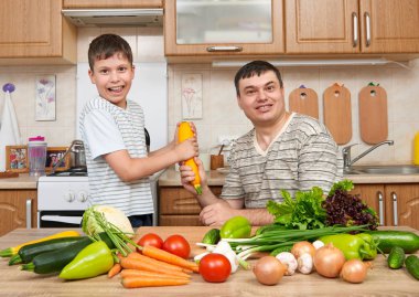 Baba ve oğul eğleniyor ile sebzeler ev mutfak iç. Adam ve çocuk. Meyve ve sebze. Sağlıklı gıda kavramı